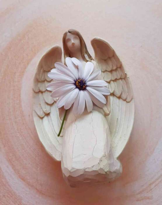 Engelfigur mit Blume – ein Symbolbild für Heilung.