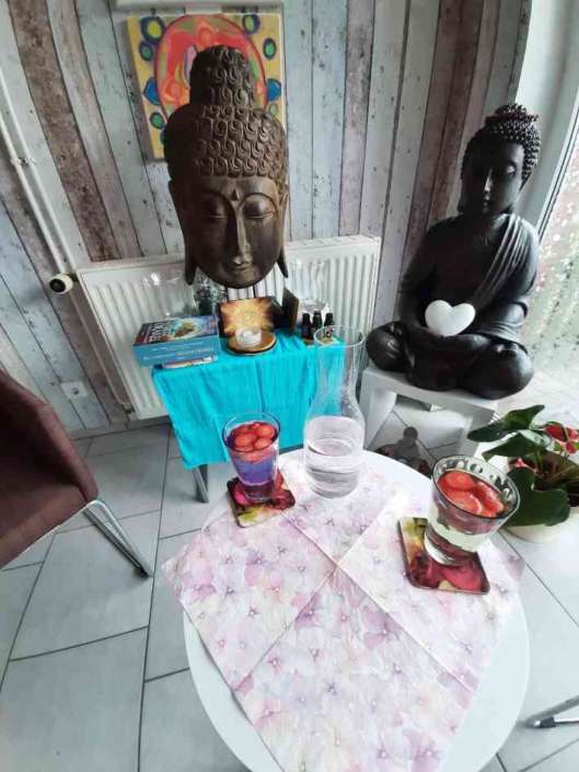 Heilpraxis Innenansicht mit Buddhafiguren und Tisch.